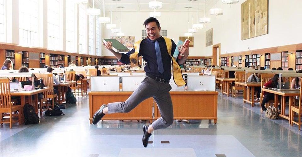 student poses with books in uc davis shields library