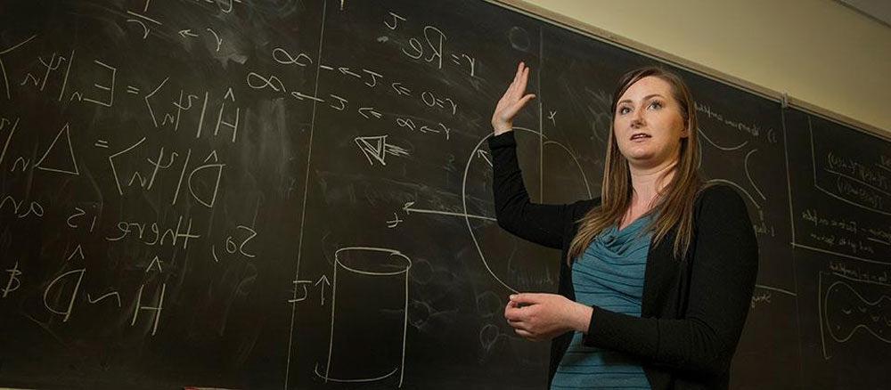 Rachel stands in front of a chalkboard while lecturing at UC Davis