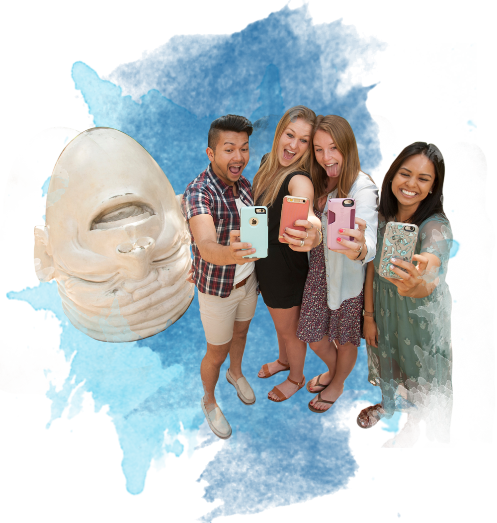 Four UCD students take a selfie next to one of our famous egghead statues.