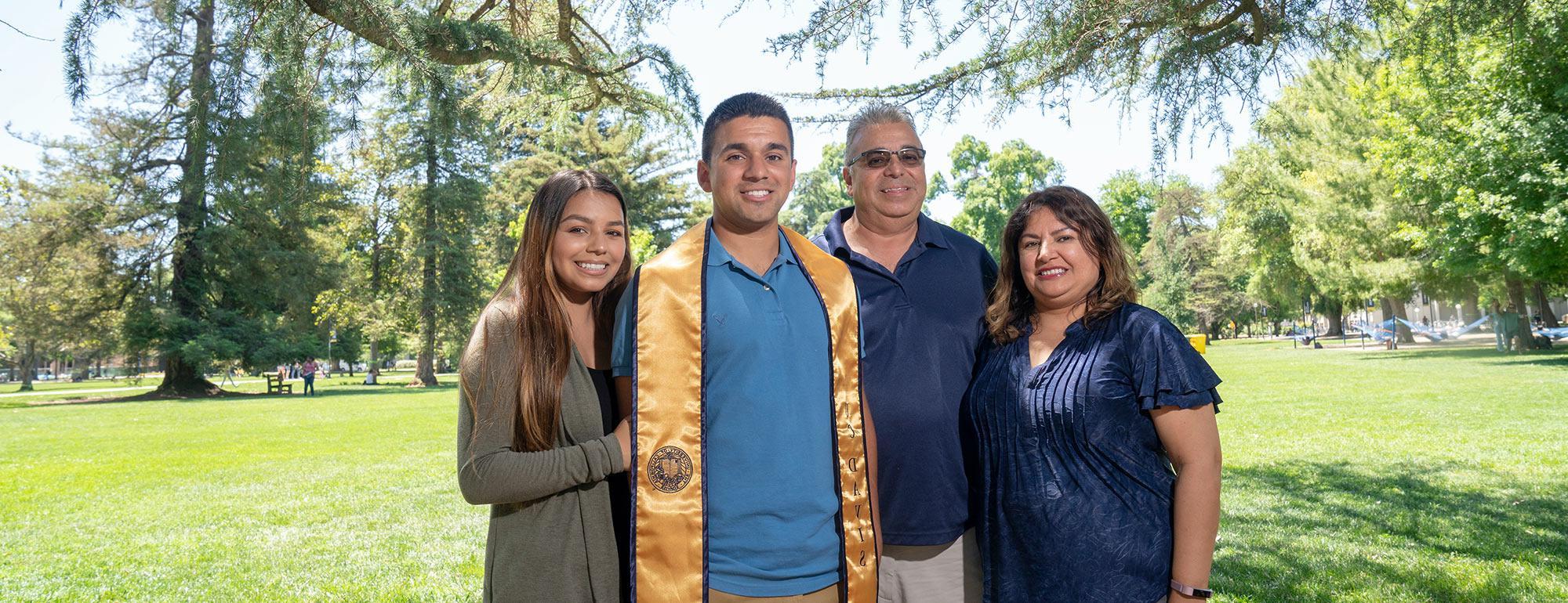 Parents pose with their UC Davis graduate son on the quad 