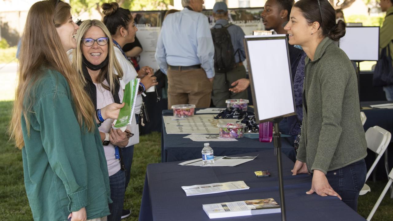 A student and parent talking with a campus representative at last year’s Aggie Day event.