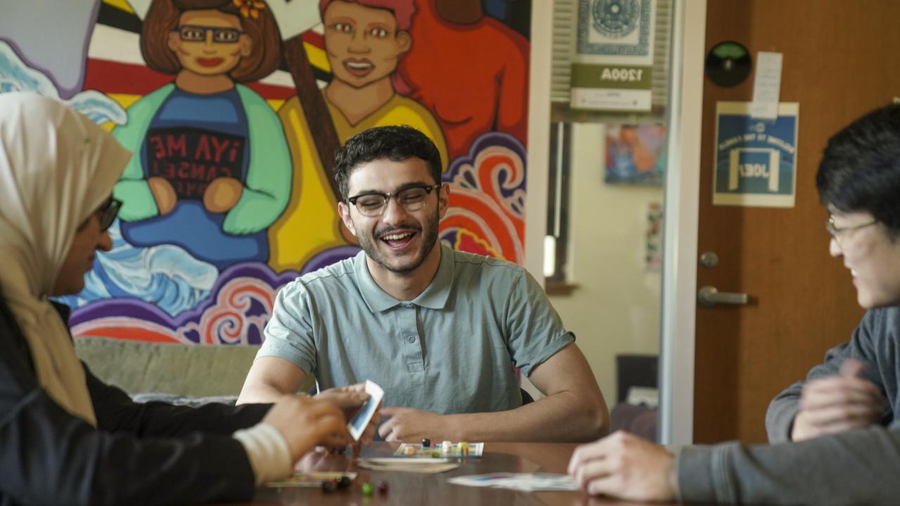 Three students laughing and hanging out while playing Lotería in one of the Cross Cultural Center’s many common areas.