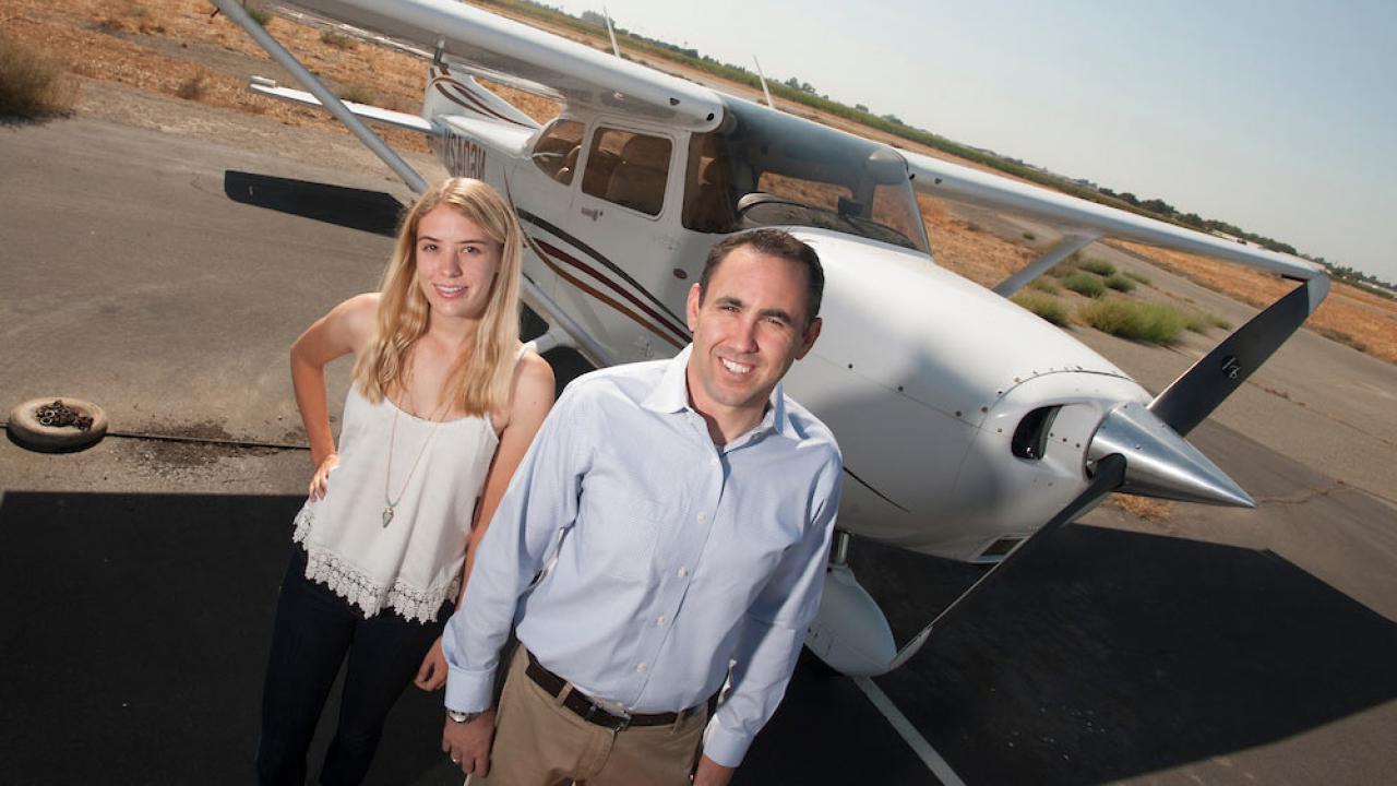 An instructor and student pose for a shot in front of an airplane at UC Davis airport