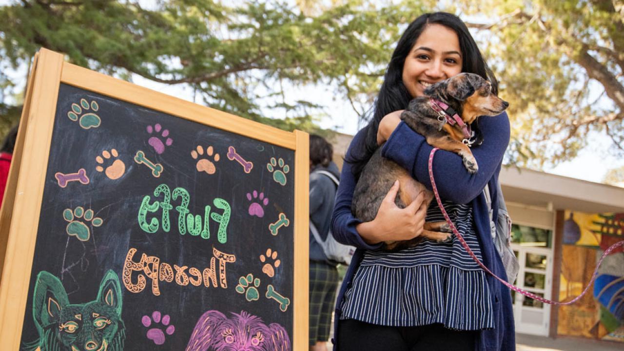 A student holds a puppy outside of the UC Davis Memorial Union