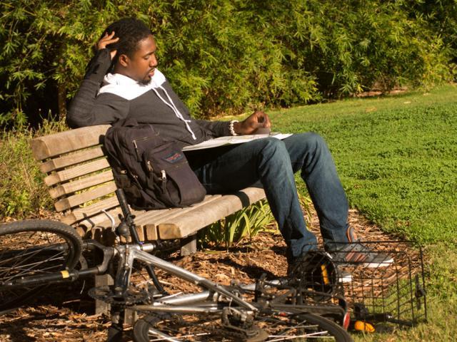 a student sitting on a bench and studying in the arboretum 