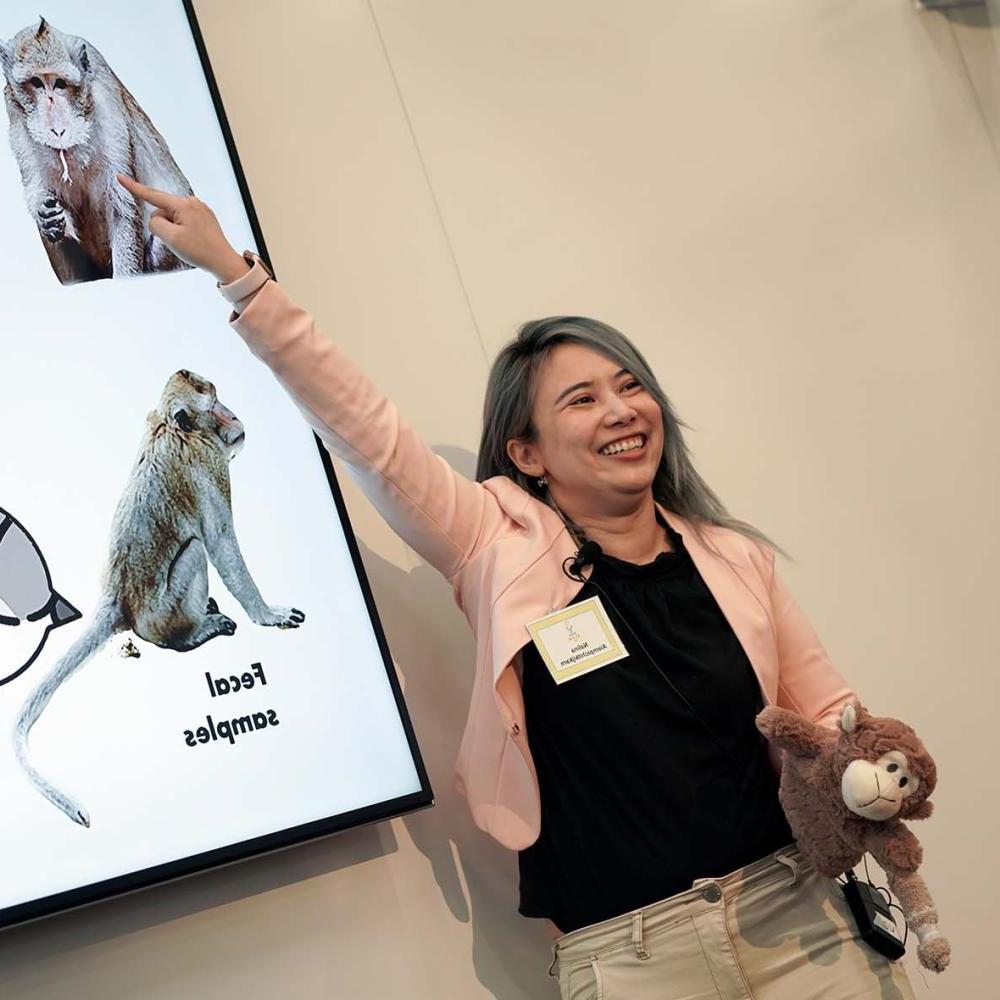 Student with plush monkey points to PowerPoint presentation.