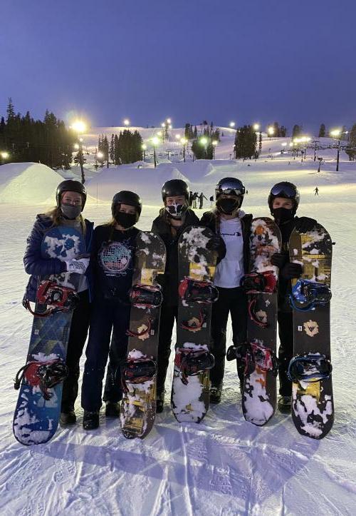 Five People Posing With Snowboards
