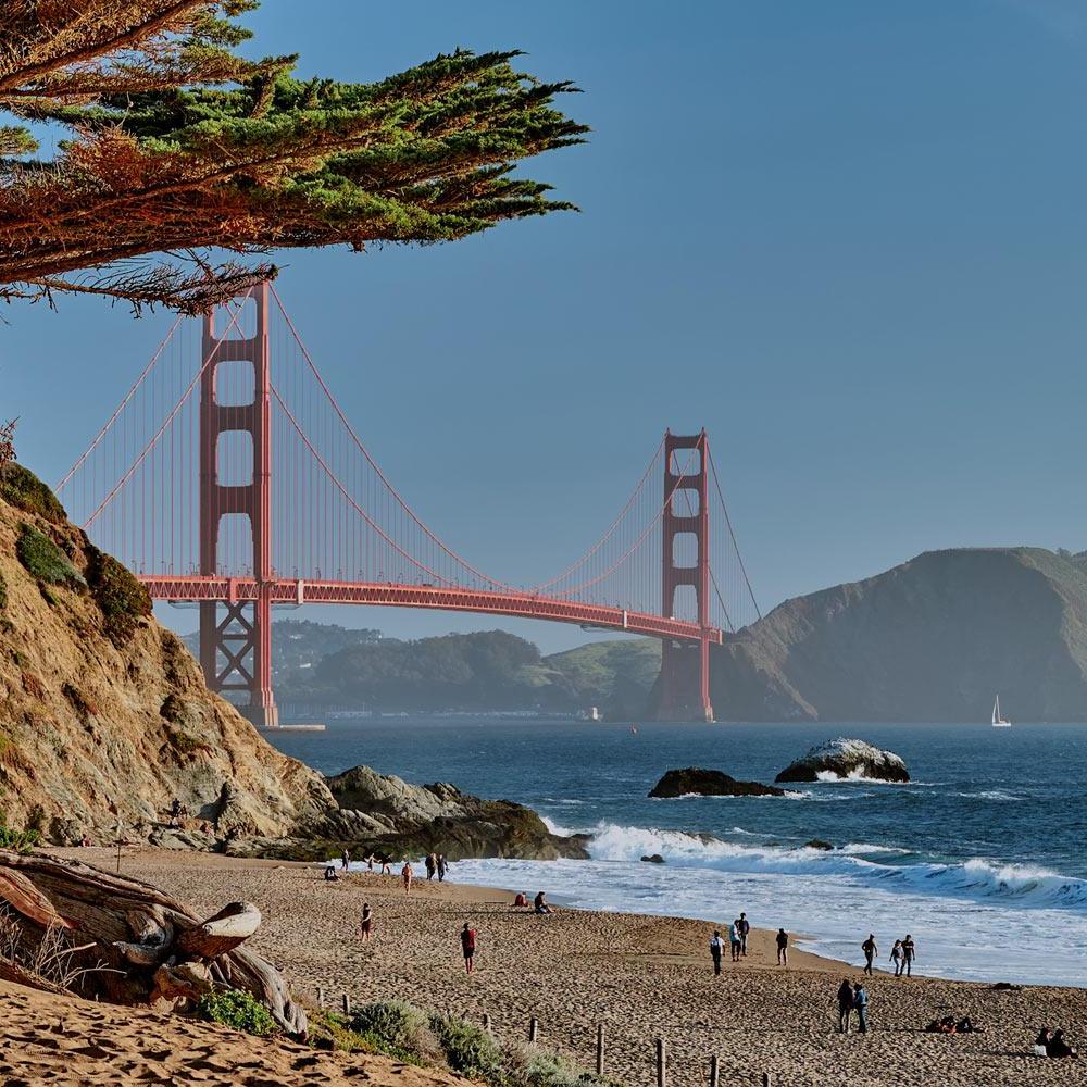 A scene of Baker Beach in San Francisco with the golden gate bridge in the background