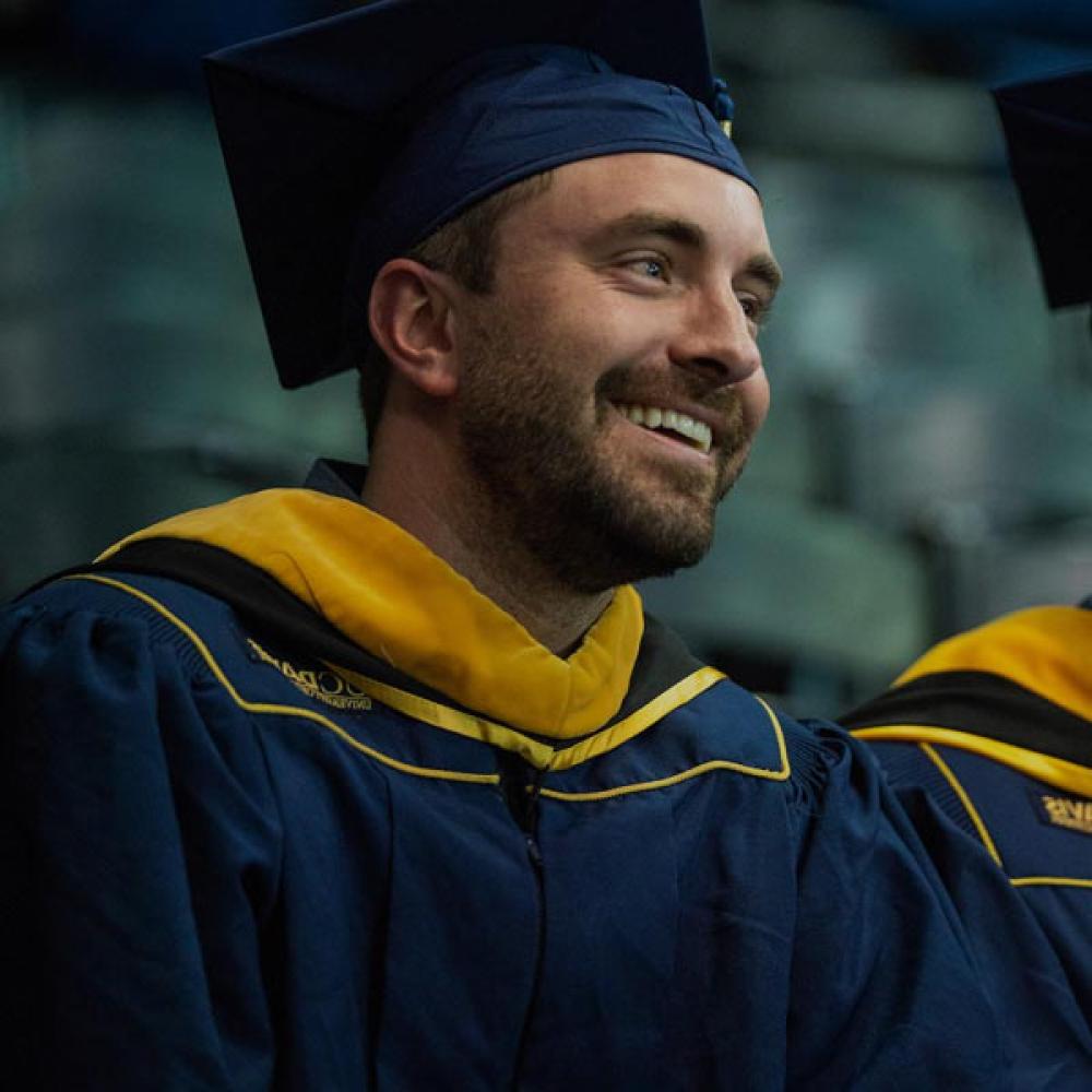 A male student smiles at his commencement ceremony