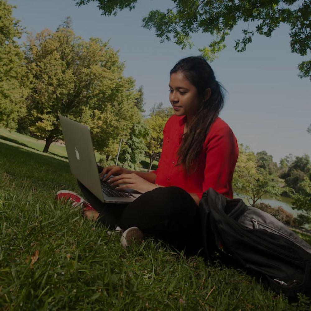 amjs澳金沙门的一名学生在她的笔记本电脑上工作