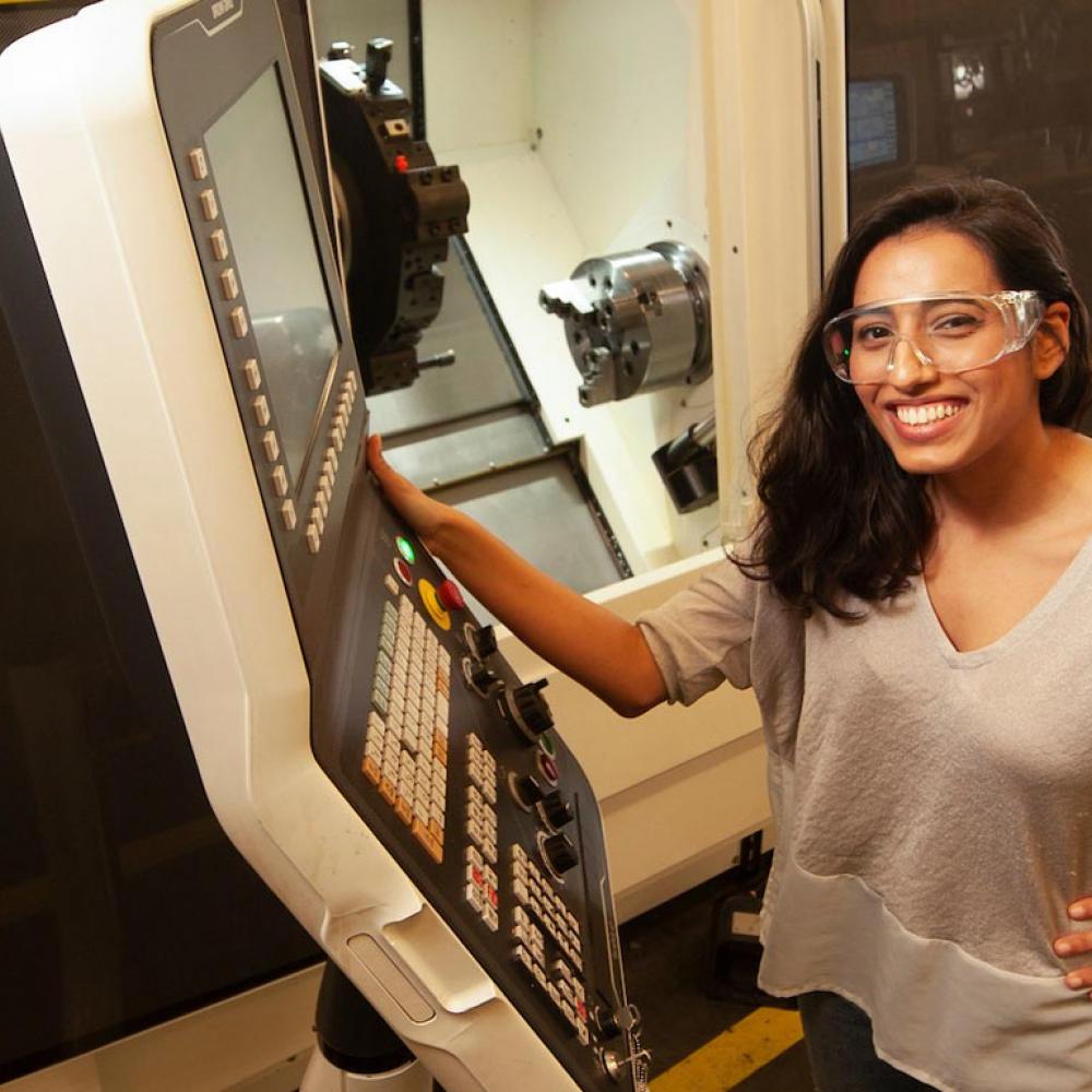 一位戴着安全眼镜的女学生正在展示一些机械